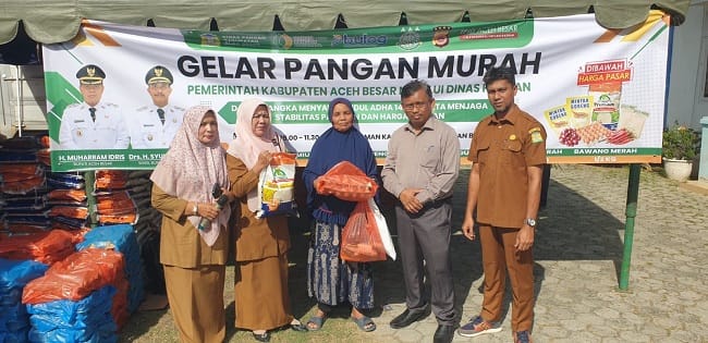 Kadis Pangan Aceh Besar Alyadi SPi MM menyerahkan secara simbolis belanja paket sembako murah yang disediakan Pemkab Aceh Besar bekerja sama dengan Perum Bulog Aceh kepada warga pada gelaran pangan murah, di Halaman Kantor Camat Peukan Bada, Selasa (5/5/2026). FOTO/ MC ACEH BESAR