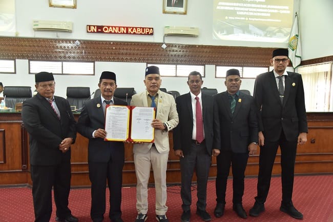 Wakil Bupati Aceh Besar Drs H Syukri didampingi Sekdakab Aceh Besar Bahrul Jamil SSos MSi foto bersama Ketua DPRK Abdul Muchti dan para Wakil Ketua DPRK Aceh Besar serta Sekretaris DPRK Aceh Besar seusai menyampaikan jawaban atas pemandangan umum Fraksi-fraksi DPRK Aceh Besar tentang Rancangan Qanun Penyertaan Modal Daerah Kabupaten Aceh Besar pada Perusahaan Umum Daerah Air Minum Tirta Mountala Kabupaten Aceh Besar di Gedung DPRK Aceh Besar, Selasa (19/5/2026). FOTO/ MC ACEH BESAR
