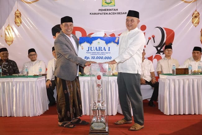 Bupati Aceh Besar H Muharram Idris menyerahkan hadiah pertama kepada Camat Blang Blang Bintang Subhan SE MM sebagai pemenang Pawai Takbiran Idul Adha 1447 H yang digelar Pemkab Aceh Besar di halaman depan Masjid Jamik Lambaro, Kecamatan Ingin Jaya, Selasa malam (26/5/2026). FOTO/PROKOPIM ACEH BESAR Bupati Aceh Besar H Muharram Idris menyerahkan hadiah pertama kepada Camat Blang Blang Bintang Subhan SE MM sebagai pemenang Pawai Takbiran Idul Adha 1447 H yang digelar Pemkab Aceh Besar di halaman depan Masjid Jamik Lambaro, Kecamatan Ingin Jaya, Selasa malam (26/5/2026). FOTO/PROKOPIM ACEH BESAR