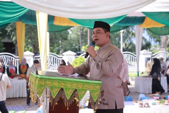 Bupati Aceh Besar, Muharram Idris menyampaikan sambutan memperingati 10 Muharram melalui tradisi memasak bubur asyura dan toet apam, di Halaman Dekranasda Aceh Besar, Kamis (25/6/2026). FOTO/PROKOPIM PEMKAB ACEH BESAR