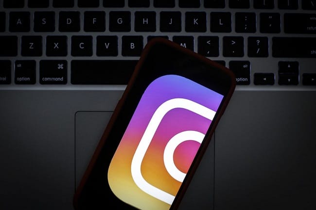 Ilustrasi logo Instagram pada ponsel yang terletak di atas laptop(Engadget)