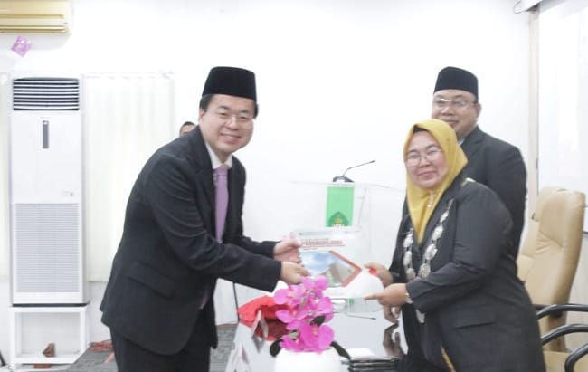 Direktur Pascasarjana UIN Ar-Raniry, Prof Eka Srimulyani saat menyerahkan tanda kelulusan Kim Young Jae, mahasiswa asal Korea Selatan yang berhasil meraih gelar Magister Ekonomi Syariah, dalam diyudisium di Aula Lantai III Gedung Pascasarjana UIN Ar-Raniry, Sabtu (13/6/2026).