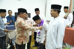 Bupati Aceh Besar, H Muharram Idris memasang sal secara simbolis kepada Jamaah Umrah para Juara MTQ dan MKQ di Gedung Dekranasda, Gampong Gani, Kecamatan Ingin Jaya, Aceh Besar, Sabtu (27/06/2026). FOTO/MC ACEH BESAR