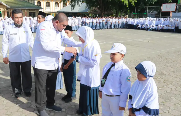 Kakankemenag Aceh Besar H Saifuddin SE mengalungkan tanda peserta Matamuda di Komplek Madrasah Terpadu Tungkop, Aceh Besar, Senin (13/7/2026). FOTO/Humas Kemenag Aceh Besar