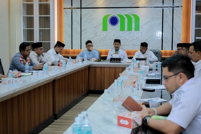 Pemkab Aceh Besar Bahas Kesiapan Kuta Baro sebagai Tuan Rumah MTQ XXXV 2026 KOTA JANTHO – Pemerintah Kabupaten Aceh Besar terus mematangkan persiapan pelaksanaan Musabaqah Tilawatil Quran (MTQ) Kabupaten Aceh Besar ke-XXXV Tahun 2026. Salah satu tahapan yang dilakukan yakni mendengarkan pemaparan kesiapan Kecamatan Kuta Baro sebagai calon tuan rumah MTQ. Pembahasan tersebut berlangsung di Aula PDAM Tirta Mountala, Rabu (12/8/2026), dipimpin Wakil Bupati Aceh Besar Drs. Syukri A. Jalil dan dihadiri sejumlah kepala Organisasi Perangkat Daerah (OPD), unsur Forkopimcam, Wakil Ketua MPU Aceh Besar, unsur mukim serta tokoh masyarakat Kuta Baro. Dalam pemaparannya, Camat Kuta Baro menyampaikan kesiapan wilayahnya sekaligus mengusulkan kawasan lapangan di depan Masjid Buengcala Seupe sebagai lokasi utama pelaksanaan MTQ. Wakil Bupati Syukri A. Jalil mengatakan pelaksanaan MTQ merupakan amanah bersama yang membutuhkan persiapan matang, koordinasi lintas sektor dan dukungan masyarakat. Menurutnya, berdasarkan hasil peninjauan lapangan dan pemaparan yang disampaikan, secara umum Kuta Baro memiliki kesiapan untuk mendukung pelaksanaan MTQ. Namun, sejumlah penyesuaian teknis tetap perlu dilakukan, terutama terkait lokasi dan kebutuhan masing-masing cabang perlombaan. “Ini menjadi amanah sekaligus tanggung jawab kita bersama. Mari kita persiapkan dengan sebaik-baiknya agar MTQ berlangsung sukses, khidmat, bermakna dan memberikan manfaat bagi masyarakat,” ujar Syukri. Ia juga meminta Dinas Syariat Islam Aceh Besar selaku leading sector bersama OPD terkait segera menindaklanjuti berbagai tahapan persiapan. Koordinasi dengan pihak kecamatan juga perlu diperkuat agar setiap kebutuhan dapat diselesaikan sejak awal. “Yang paling penting adalah komunikasi dan koordinasi. Dengan komunikasi yang intensif, setiap kebutuhan dapat dibicarakan dan diselesaikan bersama,” katanya. Masyarakat Kuta Baro Dilibatkan Syukri juga menekankan pentingnya keterlibatan masyarakat Kuta Baro dalam menyukseskan MTQ. Kecamatan diminta segera melakukan sosialisasi, sehingga masyarakat memahami rangkaian kegiatan sekaligus peran yang dapat diberikan sebagai tuan rumah. “Kita ingin masyarakat merasa ikut memiliki dan menjadi bagian dari kesuksesan pelaksanaan MTQ ini,” harapnya. Wakil Bupati juga menegaskan pentingnya memperhatikan kebutuhan masyarakat yang berkaitan dengan pelaksanaan kegiatan agar MTQ memberikan dampak positif bagi daerah dan berlangsung dengan suasana yang nyaman bagi masyarakat maupun para peserta. Lebih lanjut, Syukri berharap MTQ ke-XXXV tidak hanya menjadi ajang perlombaan, tetapi juga momentum memperkuat syiar Islam dan meningkatkan kecintaan generasi muda terhadap Al-Quran. Ia optimistis antusiasme masyarakat akan tinggi, termasuk dari Banda Aceh dan wilayah lainnya. Kemudahan akses menuju Kuta Baro juga dinilai dapat mendukung kehadiran masyarakat untuk menyaksikan rangkaian MTQ. “Dengan kebersamaan, koordinasi dan kekompakan seluruh pihak, insyaallah MTQ Aceh Besar ke-XXXV dapat berjalan sesuai harapan dan memberikan hasil maksimal untuk syiar Islam,” katanya. Syukri menambahkan, seluruh kebutuhan teknis seperti penetapan cabang perlombaan, lokasi, logo dan tema MTQ perlu segera dituntaskan agar informasi tersebut dapat disosialisasikan kepada masyarakat. Untuk itu, ia mengajak seluruh panitia, OPD, unsur kecamatan, tokoh masyarakat dan seluruh elemen terkait untuk bersama-sama menyukseskan MTQ Kabupaten Aceh Besar ke-XXXV Tahun 2026. “Dengan kebersamaan dan semangat melayani masyarakat, insyaallah MTQ ini dapat terlaksana dengan baik dan menjadi momentum syiar Islam yang membawa keberkahan bagi kita semua,” pungkasnya.(**) Wakil Bupati Aceh Besar Drs. Syukri A. Jalil memimpin rapat persiapan pelaksanaan MTQ Kabupaten Aceh Besar ke-XXXV Tahun 2026, dengan tuan rumah Kecamatan Kuta Baro, di Aula PDAM Tirta Mountala, Rabu (12/8/2026), FOTO/ MC ACEH BESAR Suasana rapat Pemkab Aceh Besar bersama OPD terkait dan unsur Kecamatan Kuta Baro dalam membahas persiapan pelaksanaan MTQ Aceh Besar ke-XXXV Tahun 2026, di Aula PDAM Tirta Mountala, Rabu (12/8/2026). FOTO/ MC ACEH BESAR Pemkab Aceh Besar Bahas Kesiapan Kuta Baro sebagai Tuan Rumah MTQ XXXV 2026 KOTA JANTHO – Pemerintah Kabupaten Aceh Besar terus mematangkan persiapan pelaksanaan Musabaqah Tilawatil Quran (MTQ) Kabupaten Aceh Besar ke-XXXV Tahun 2026. Salah satu tahapan yang dilakukan yakni mendengarkan pemaparan kesiapan Kecamatan Kuta Baro sebagai calon tuan rumah MTQ. Pembahasan tersebut berlangsung di Aula PDAM Tirta Mountala, Rabu (12/8/2026), dipimpin Wakil Bupati Aceh Besar Drs. Syukri A. Jalil dan dihadiri sejumlah kepala Organisasi Perangkat Daerah (OPD), unsur Forkopimcam, Wakil Ketua MPU Aceh Besar, unsur mukim serta tokoh masyarakat Kuta Baro. Dalam pemaparannya, Camat Kuta Baro menyampaikan kesiapan wilayahnya sekaligus mengusulkan kawasan lapangan di depan Masjid Buengcala Seupe sebagai lokasi utama pelaksanaan MTQ. Wakil Bupati Syukri A. Jalil mengatakan pelaksanaan MTQ merupakan amanah bersama yang membutuhkan persiapan matang, koordinasi lintas sektor dan dukungan masyarakat. Menurutnya, berdasarkan hasil peninjauan lapangan dan pemaparan yang disampaikan, secara umum Kuta Baro memiliki kesiapan untuk mendukung pelaksanaan MTQ. Namun, sejumlah penyesuaian teknis tetap perlu dilakukan, terutama terkait lokasi dan kebutuhan masing-masing cabang perlombaan. “Ini menjadi amanah sekaligus tanggung jawab kita bersama. Mari kita persiapkan dengan sebaik-baiknya agar MTQ berlangsung sukses, khidmat, bermakna dan memberikan manfaat bagi masyarakat,” ujar Syukri. Ia juga meminta Dinas Syariat Islam Aceh Besar selaku leading sector bersama OPD terkait segera menindaklanjuti berbagai tahapan persiapan. Koordinasi dengan pihak kecamatan juga perlu diperkuat agar setiap kebutuhan dapat diselesaikan sejak awal. “Yang paling penting adalah komunikasi dan koordinasi. Dengan komunikasi yang intensif, setiap kebutuhan dapat dibicarakan dan diselesaikan bersama,” katanya. Masyarakat Kuta Baro Dilibatkan Syukri juga menekankan pentingnya keterlibatan masyarakat Kuta Baro dalam menyukseskan MTQ. Kecamatan diminta segera melakukan sosialisasi, sehingga masyarakat memahami rangkaian kegiatan sekaligus peran yang dapat diberikan sebagai tuan rumah. “Kita ingin masyarakat merasa ikut memiliki dan menjadi bagian dari kesuksesan pelaksanaan MTQ ini,” harapnya. Wakil Bupati juga menegaskan pentingnya memperhatikan kebutuhan masyarakat yang berkaitan dengan pelaksanaan kegiatan agar MTQ memberikan dampak positif bagi daerah dan berlangsung dengan suasana yang nyaman bagi masyarakat maupun para peserta. Lebih lanjut, Syukri berharap MTQ ke-XXXV tidak hanya menjadi ajang perlombaan, tetapi juga momentum memperkuat syiar Islam dan meningkatkan kecintaan generasi muda terhadap Al-Quran. Ia optimistis antusiasme masyarakat akan tinggi, termasuk dari Banda Aceh dan wilayah lainnya. Kemudahan akses menuju Kuta Baro juga dinilai dapat mendukung kehadiran masyarakat untuk menyaksikan rangkaian MTQ. “Dengan kebersamaan, koordinasi dan kekompakan seluruh pihak, insyaallah MTQ Aceh Besar ke-XXXV dapat berjalan sesuai harapan dan memberikan hasil maksimal untuk syiar Islam,” katanya. Syukri menambahkan, seluruh kebutuhan teknis seperti penetapan cabang perlombaan, lokasi, logo dan tema MTQ perlu segera dituntaskan agar informasi tersebut dapat disosialisasikan kepada masyarakat. Untuk itu, ia mengajak seluruh panitia, OPD, unsur kecamatan, tokoh masyarakat dan seluruh elemen terkait untuk bersama-sama menyukseskan MTQ Kabupaten Aceh Besar ke-XXXV Tahun 2026. “Dengan kebersamaan dan semangat melayani masyarakat, insyaallah MTQ ini dapat terlaksana dengan baik dan menjadi momentum syiar Islam yang membawa keberkahan bagi kita semua,” pungkasnya.(**) Wakil Bupati Aceh Besar Drs. Syukri A. Jalil memimpin rapat persiapan pelaksanaan MTQ Kabupaten Aceh Besar ke-XXXV Tahun 2026, dengan tuan rumah Kecamatan Kuta Baro, di Aula PDAM Tirta Mountala, Rabu (12/8/2026), FOTO/ MC ACEH BESAR Suasana rapat Pemkab Aceh Besar bersama OPD terkait dan unsur Kecamatan Kuta Baro dalam membahas persiapan pelaksanaan MTQ Aceh Besar ke-XXXV Tahun 2026, di Aula PDAM Tirta Mountala, Rabu (12/8/2026). FOTO/ MC ACEH BESAR