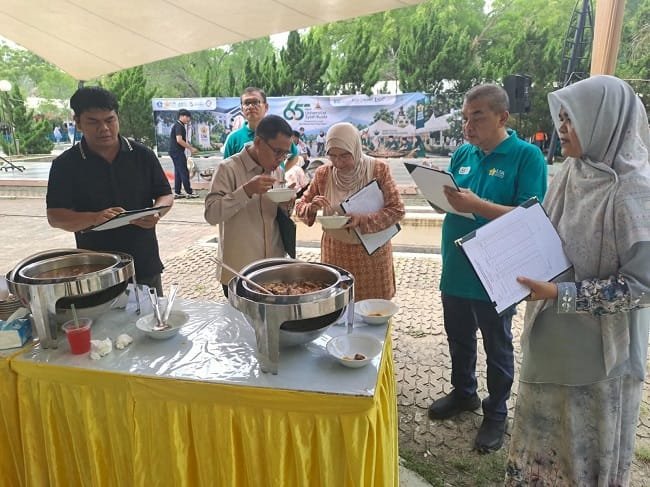 Kabid Kebudayaan Disdikbud Aceh Besar, Cut Jarita Susanti SPd, bersama T Raden Sulaiman, melakukan penilaian terhadap masakan kuah beulangong dari peserta, di halaman AAC Dayan Dawood, Banda Aceh, Minggu (20/9/2026). FOTO/ MC ACEH BESAR