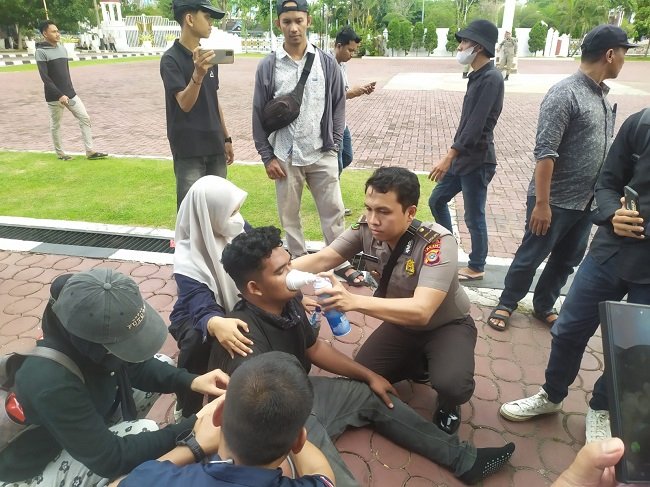 Personel Biddokkes Polda Aceh memberikan pertolongan awal kepada peserta aksi yang mengalami gangguan pernapasan saat unjuk rasa di Kantor Gubernur Aceh, Banda Aceh, Selasa, 20/10/2026.