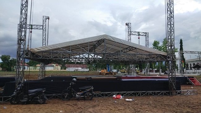 Progres pemasangan panggung utama MTQ ke-35 tingkat Kabupaten Aceh Besar Tahun 2026 di Lapangan Bola Gampong Seupeu, Kecamatan Kuta Baro, Rabu (21/10/2026). FOTO/ MC ACEH BESAR