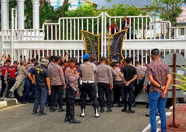 Personel Polda Aceh menahan gerbang kantor Gubernur Aceh, sambil melantunkan solawat, Rabu 20/10/2026.