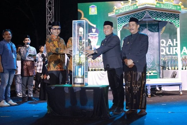 Bupati Aceh Besar H. Muharram Idris menyerahkan piala bergilir kepada Camat Peukan Bada, Salamuddin ZM, SE usai menjadi Juara Umum MTQ ke-35 Tingkat Kabupaten Aceh Besar pada malam penutupan di arena utama, Lapangan Kemukiman Bung Cala, Kecamatan Kuta Baro, Jumat (30/10/2026) Bupati Aceh Besar H. Muharram Idris menyerahkan piala bergilir kepada Camat Peukan Bada, Salamuddin ZM, SE usai menjadi Juara Umum MTQ ke-35 Tingkat Kabupaten Aceh Besar pada malam penutupan di arena utama, Lapangan Kemukiman Bung Cala, Kecamatan Kuta Baro, Jumat (30/10/2026)